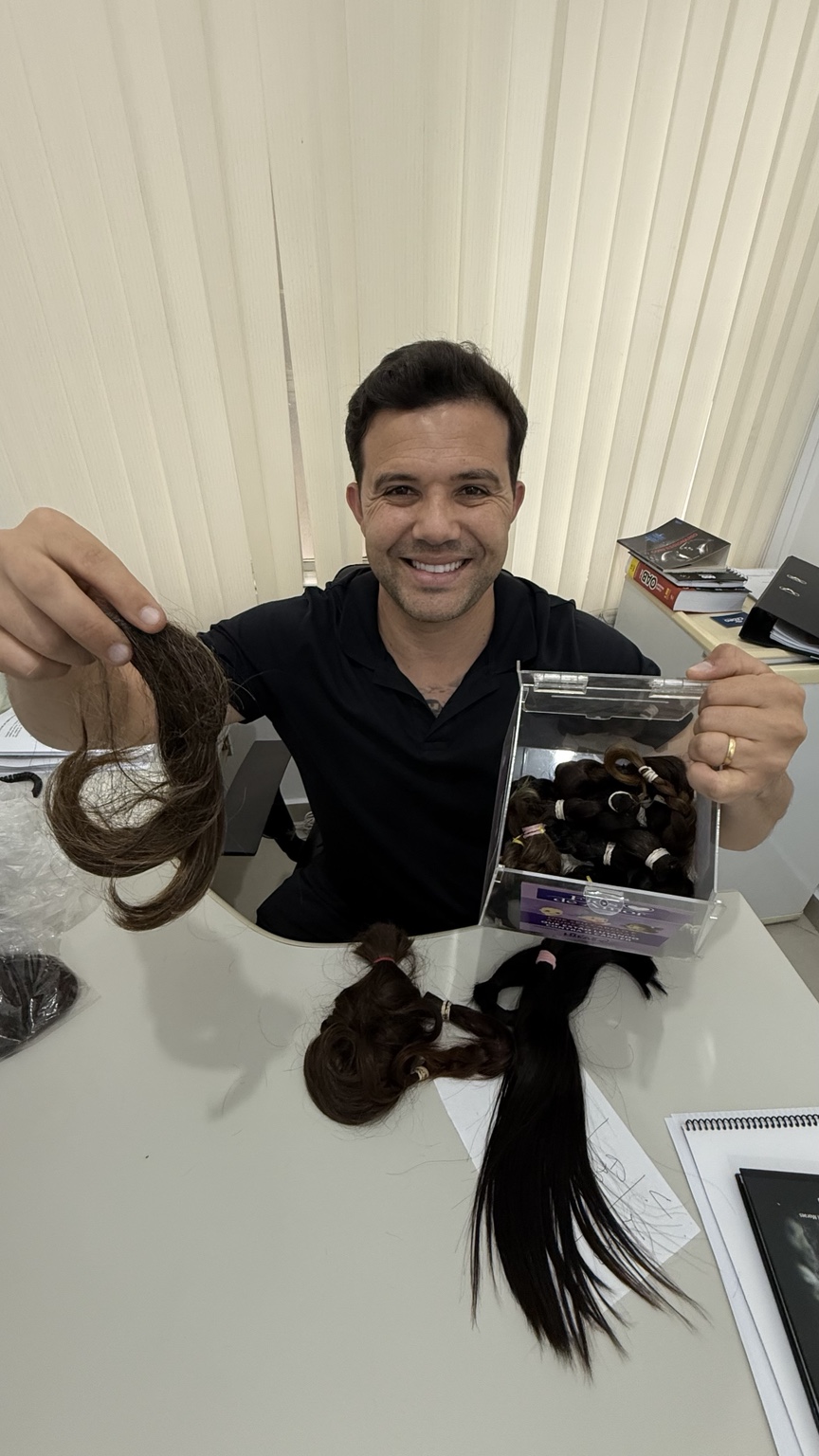 Lucas Cardoso mostrando mechas de cabelo arrecadadas para doação na campanha Fios de Amor